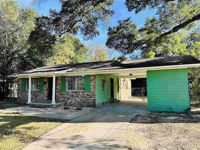 ranch-style house featuring covered porch and a carport