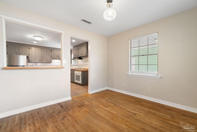 unfurnished living room with visible vents, baseboards, and wood finished floors