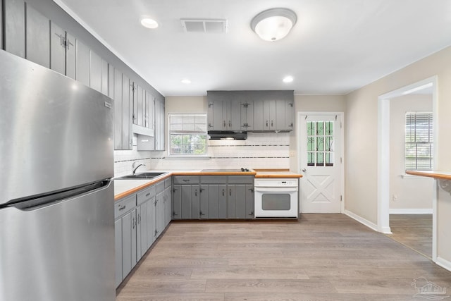 kitchen featuring oven, visible vents, light wood-type flooring, gray cabinetry, and freestanding refrigerator