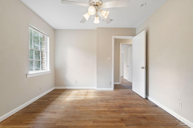 spare room featuring a ceiling fan, light wood-type flooring, and baseboards