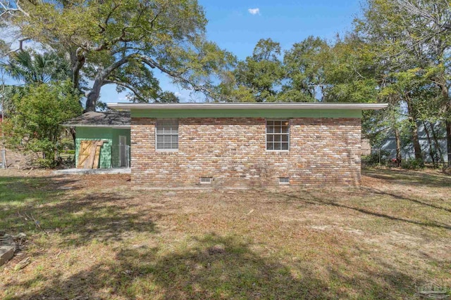 view of side of property featuring crawl space, a yard, and brick siding