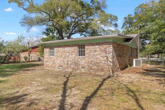 view of side of property featuring crawl space, brick siding, central AC unit, and a lawn