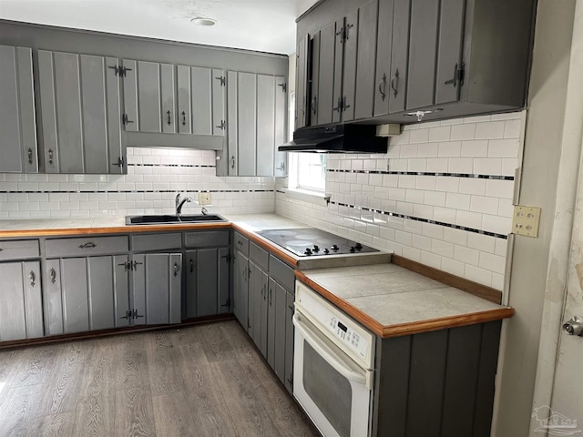 kitchen featuring tile countertops, white appliances, gray cabinetry, and a sink