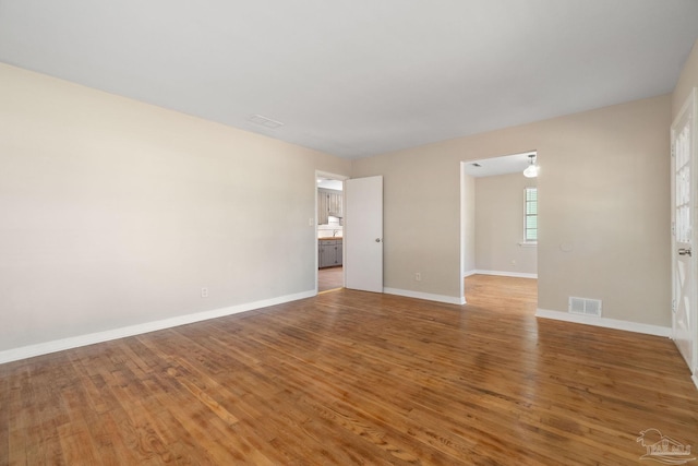 empty room featuring visible vents, light wood-style flooring, and baseboards