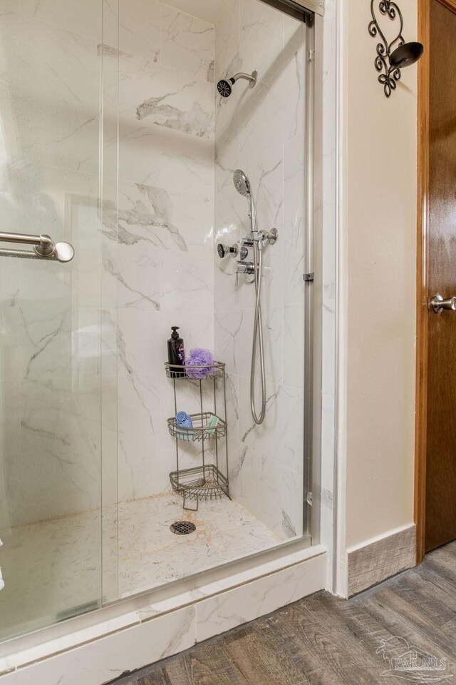 bathroom with a shower with door and wood-type flooring