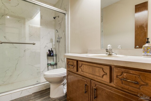 bathroom featuring vanity, toilet, wood-type flooring, and walk in shower