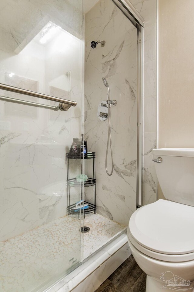 bathroom with a shower with door, toilet, and hardwood / wood-style floors