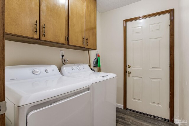 washroom with washer and dryer, a textured ceiling, dark hardwood / wood-style flooring, and cabinets