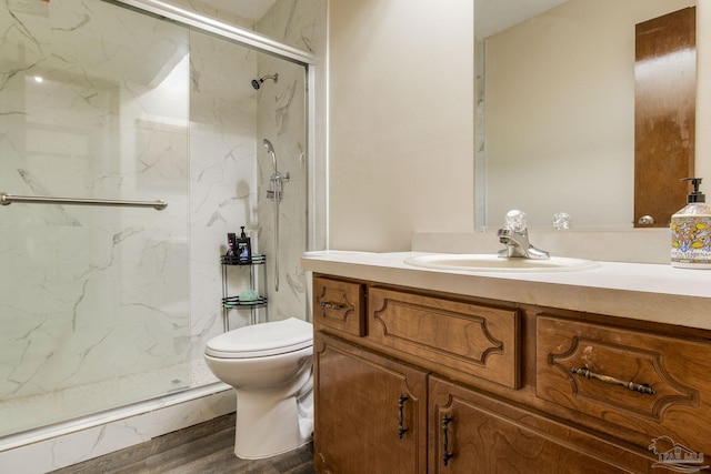 bathroom with vanity, toilet, a shower with shower door, and hardwood / wood-style floors