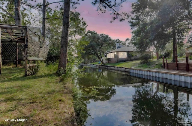 dock area with a lawn and a water view