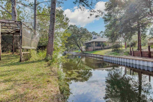 view of dock with a yard and a water view