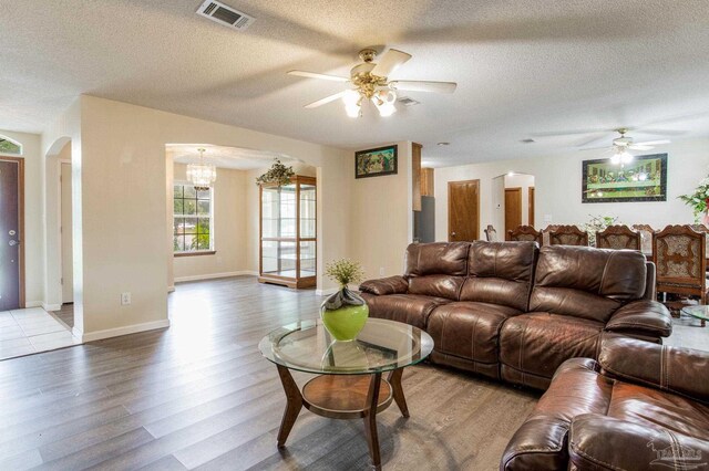 living room with a textured ceiling, ceiling fan with notable chandelier, and hardwood / wood-style floors