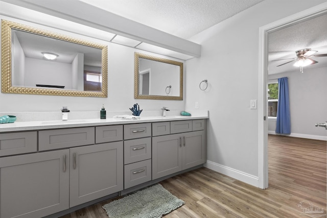 5732 Dove Dr, Pace, FL 32571 - bathroom featuring a textured ceiling, wood finished floors, baseboards, double vanity, and a ceiling fan