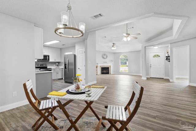 5732 Dove Dr, Pace, FL 32571 - dining room with light wood-style flooring, baseboards, a ceiling fan, a glass covered fireplace, and a chandelier