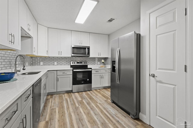 5732 Dove Dr, Pace, FL 32571 - kitchen featuring stainless steel appliances, a sink, light countertops, light wood-type flooring, and tasteful backsplash