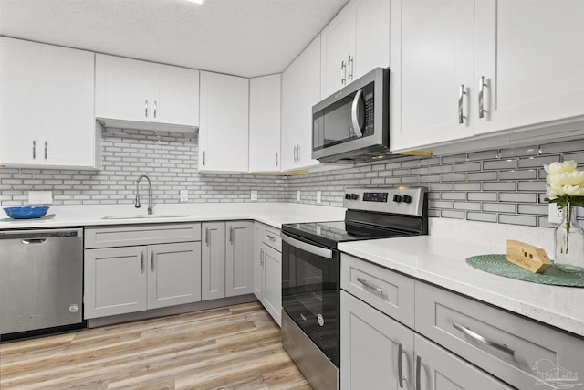 5732 Dove Dr, Pace, FL 32571 - kitchen with stainless steel appliances, a sink, light countertops, decorative backsplash, and gray cabinetry
