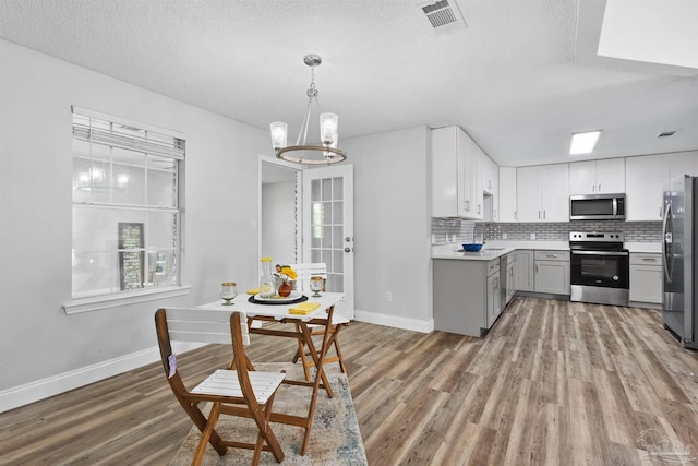 5732 Dove Dr, Pace, FL 32571 - kitchen featuring stainless steel appliances, light wood-type flooring, baseboards, gray cabinets, and a textured ceiling