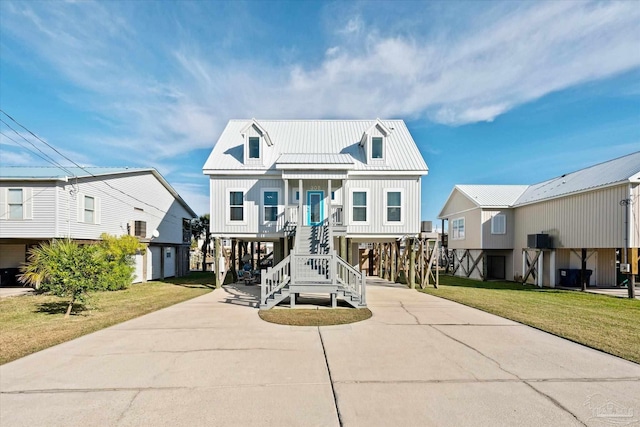 raised beach house with a front yard, a garage, and a porch