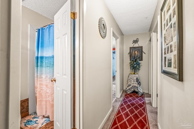 corridor with a textured ceiling and carpet