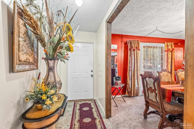 foyer entrance featuring a textured ceiling and carpet flooring