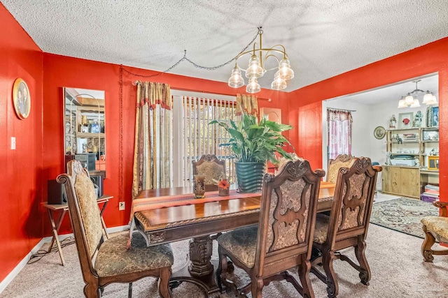 dining room featuring a textured ceiling, carpet flooring, and a notable chandelier