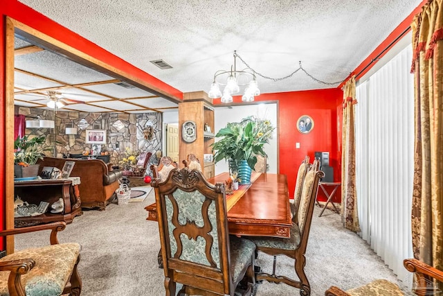 carpeted dining area with ceiling fan with notable chandelier and a textured ceiling