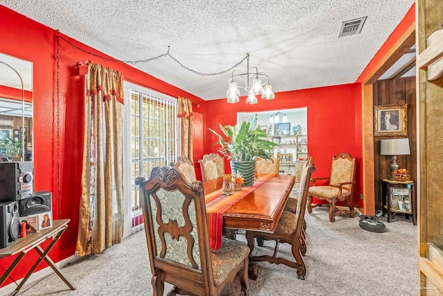 carpeted dining room with a chandelier and a textured ceiling