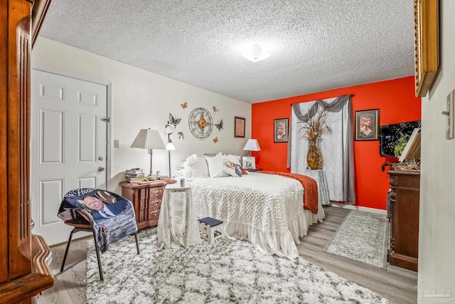 bedroom with light wood-type flooring and a textured ceiling