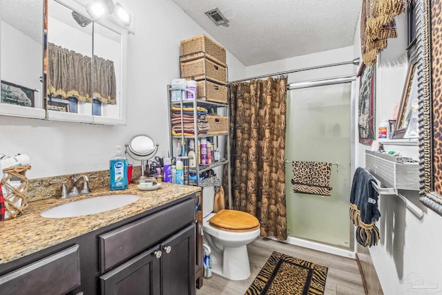 bathroom featuring vanity, wood-type flooring, a textured ceiling, toilet, and a shower with shower curtain