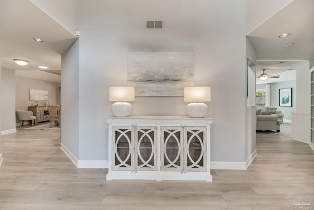 hall with visible vents, baseboards, and wood finished floors