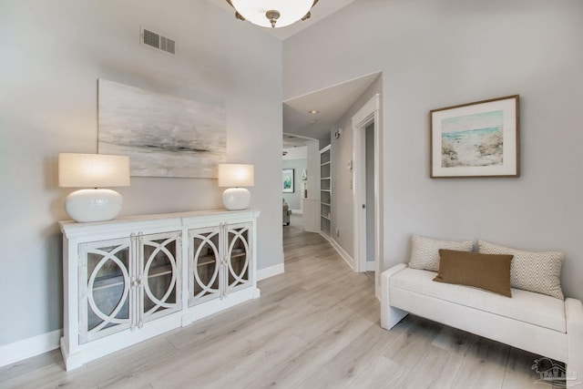 corridor featuring visible vents, baseboards, and wood finished floors