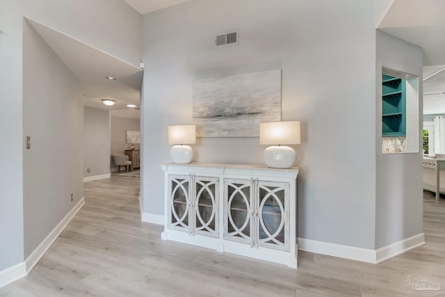 corridor with visible vents, baseboards, and wood finished floors