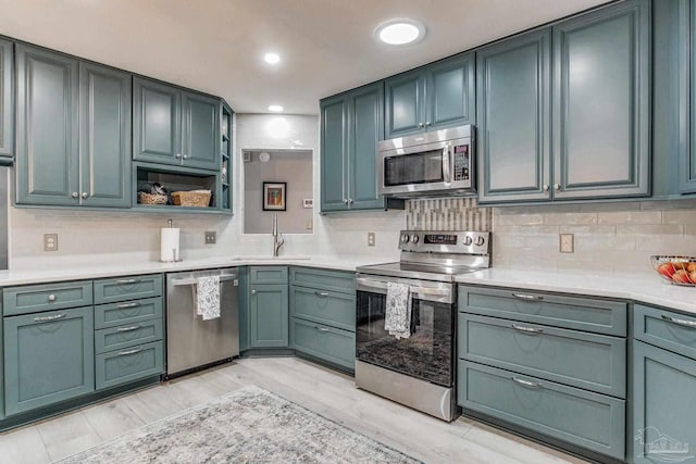 kitchen featuring light countertops, decorative backsplash, recessed lighting, stainless steel appliances, and a sink