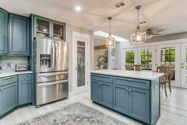 kitchen with ceiling fan, pendant lighting, light countertops, french doors, and stainless steel fridge