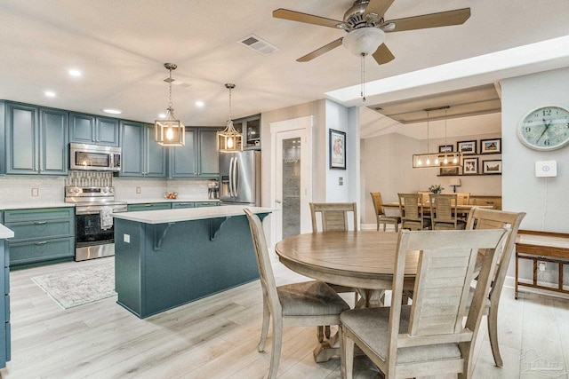 kitchen featuring visible vents, stainless steel appliances, light wood finished floors, decorative backsplash, and light countertops