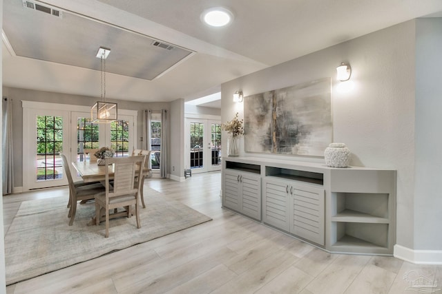 dining space with baseboards, visible vents, french doors, a raised ceiling, and light wood-type flooring