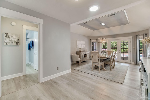 dining room featuring light wood finished floors, visible vents, baseboards, a tray ceiling, and french doors