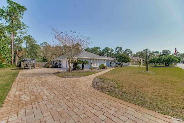 ranch-style home with an attached garage, decorative driveway, and a front yard