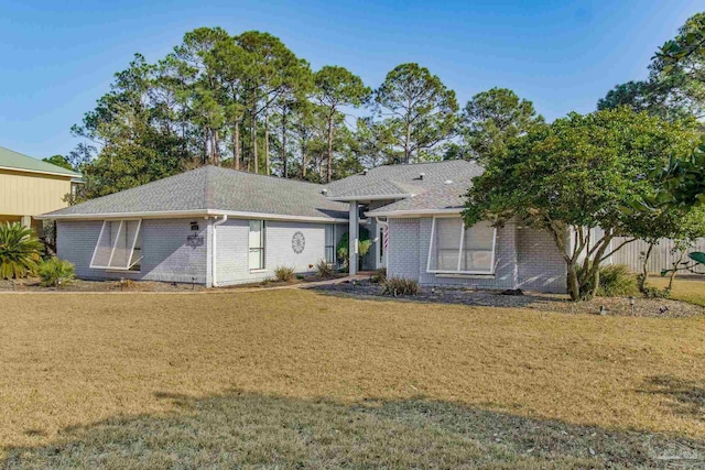 ranch-style house with a front yard, brick siding, and roof with shingles