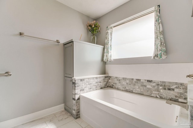 full bathroom with baseboards, a garden tub, and marble finish floor