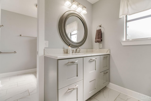 bathroom with marble finish floor, vanity, and baseboards