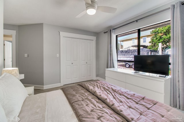 bedroom with ceiling fan, a closet, baseboards, and wood finished floors