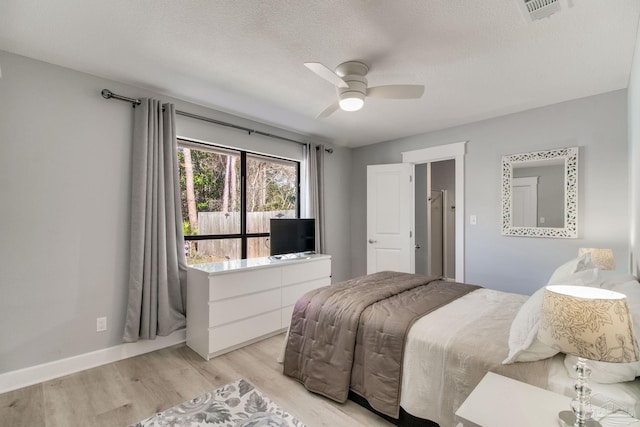 bedroom with a ceiling fan, baseboards, visible vents, light wood-style flooring, and a textured ceiling