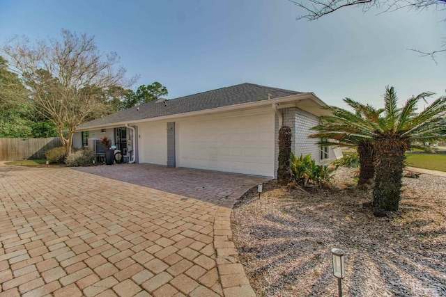 view of front of home with brick siding, an attached garage, decorative driveway, and fence