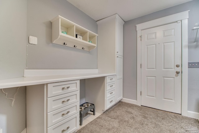 unfurnished office featuring light colored carpet and built in desk