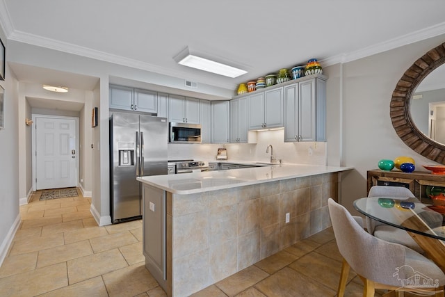 kitchen with ornamental molding, stainless steel appliances, kitchen peninsula, and sink