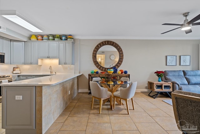 kitchen with appliances with stainless steel finishes, gray cabinets, kitchen peninsula, and sink