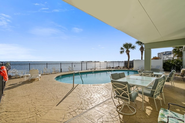 view of pool with a water view and a patio