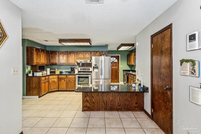 kitchen featuring kitchen peninsula, light tile patterned floors, stainless steel appliances, and a textured ceiling