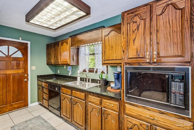 kitchen with sink, light tile patterned floors, black appliances, and a textured ceiling